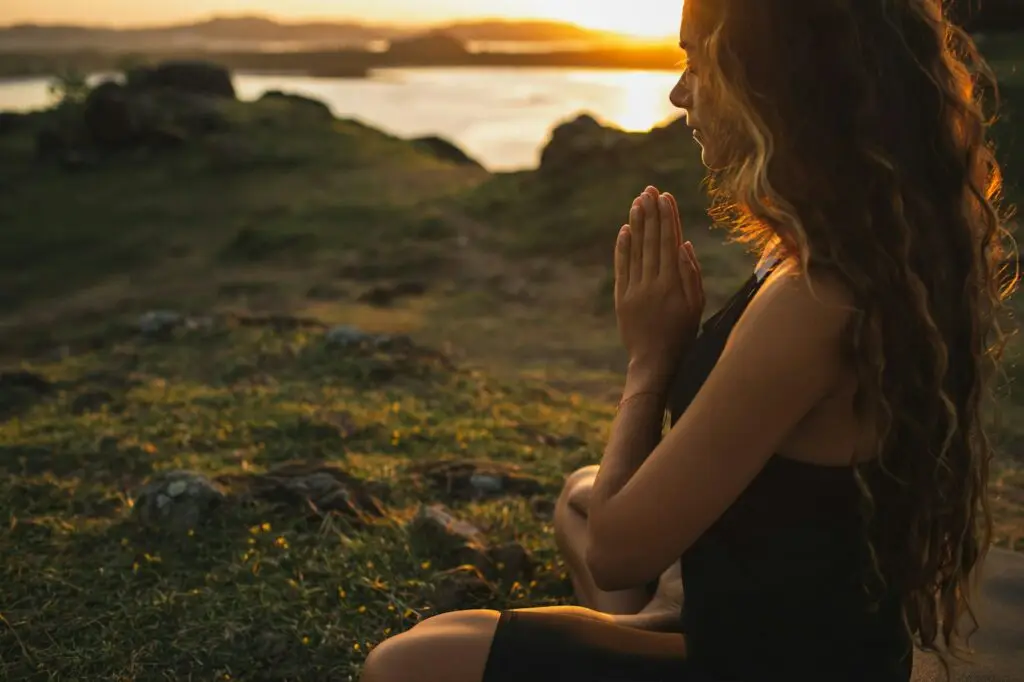 Woman praying alone at sunrise. Nature background. Spiritual and emotional concept.